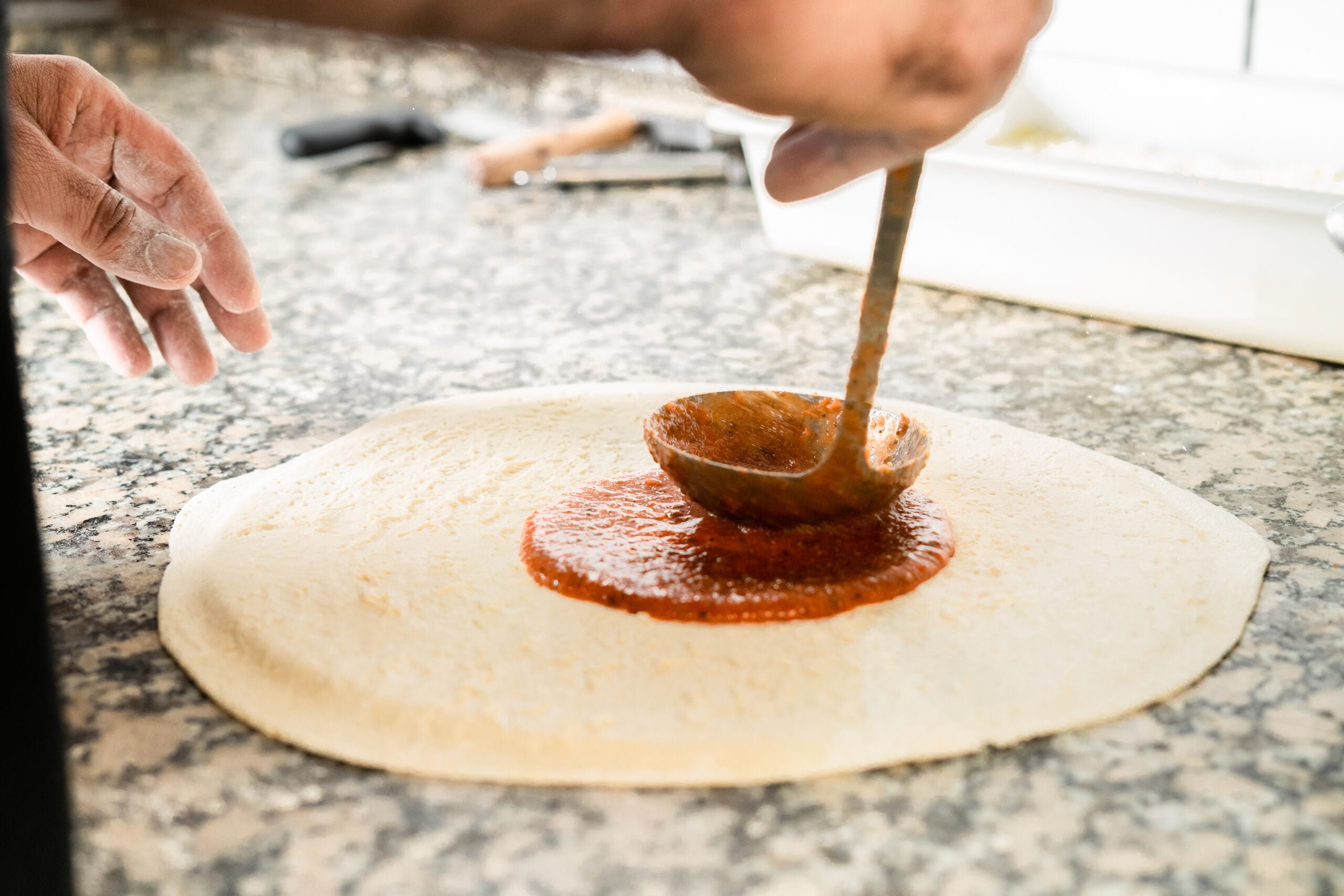 Preparando una pizza poniendo y expandiendo la sala de tomate