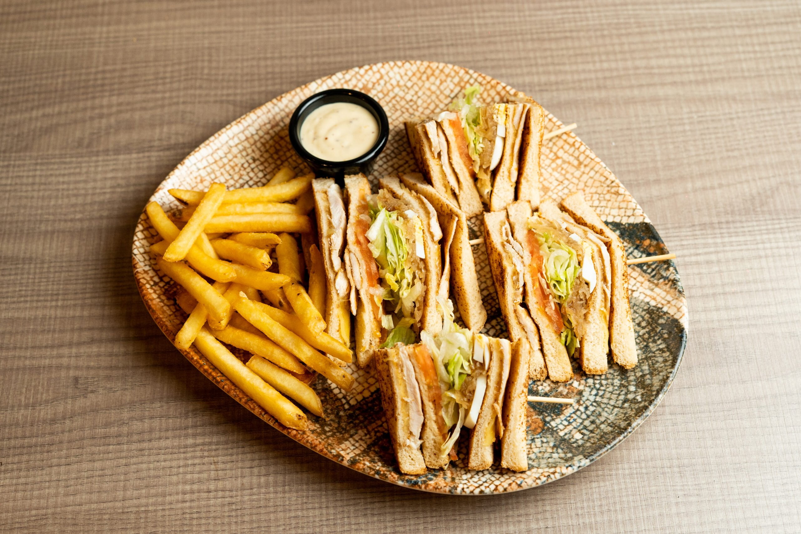 Plato con varios sándwiches acompañado con salsa y patatas